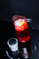 punch with fruits and ice in glasses and pincher. Homemade refreshing fruit sangria over rustic wooden table,