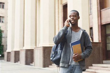 Happy african-american student talking on smartphone in campus