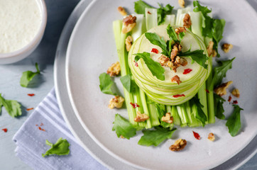 Delicious Waldorf Salad topped with roasted walnuts and watercress sprigs on white plate. top view,close-up