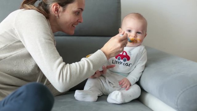 Mother, feeding her baby boy with mashed pumpking for the first time