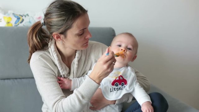 Mother, feeding her baby boy with mashed pumpking for the first time