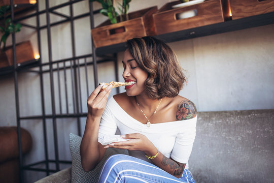 Young cuban woman eating pizza in cafe