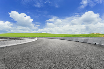 Asphalt pavements and prairies under the blue sky and white clouds