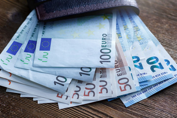 Euro banknotes in a purse on a wooden table