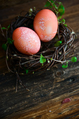 Easter decor, background: painted red eggs in a decorative nest with branches of greenery, the concept of the spring festival, the arrival of spring. The layout for your text.