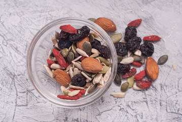 Close up of a Mixed of Nuts, Dry Fruits in glass Bowl on Gray Textured Background. top view.