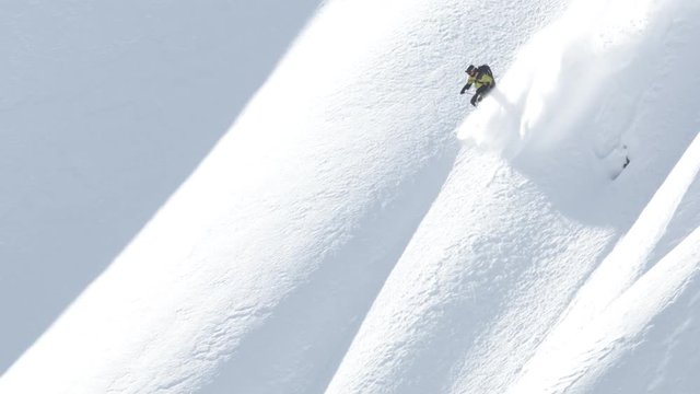 Slow motion aerial, skier on snowy mountainside