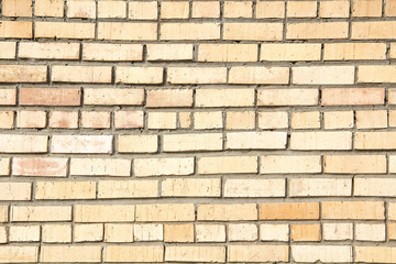 The texture of the old brick wall with concrete seams on a clear sunny day.