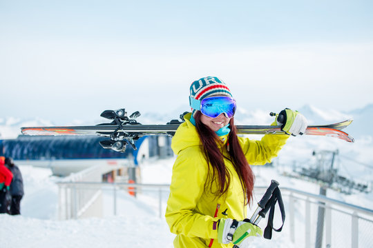 Photo of smiling sports woman with skis on her shoulder