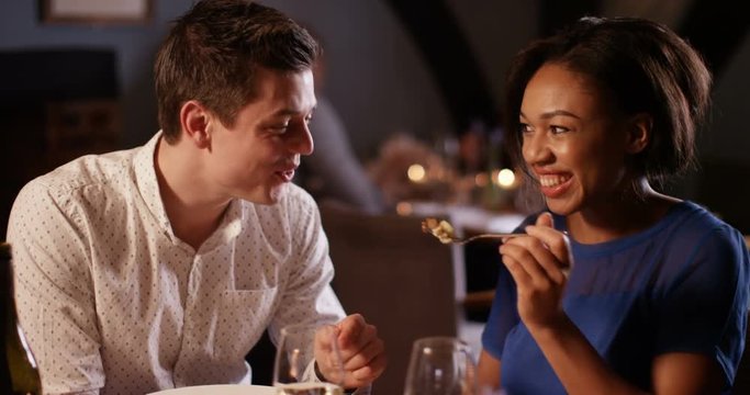 4K Romantic couple enjoying a meal out, woman feeds her partner with a taster from her plate. Slow motion