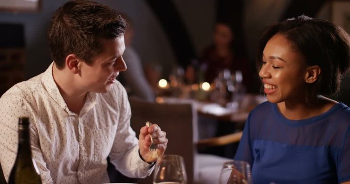 4K Sensual couple enjoying a meal out, man feeds his partner with a taster from his plate. Slow motion