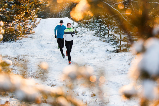 Photo of running sports woman and man in winter park