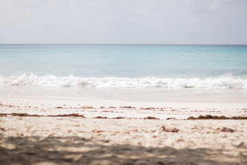 It's a nice sunny day on a sandy beach with white sea foam of warm sea. The skyline line is visible. Concept: Travel and vacation.