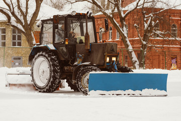 A tractor with brushes removes snow on the rink