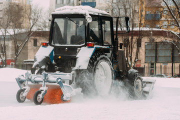 A tractor with brushes removes snow on the rink