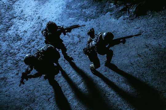 Black silhouette of soldiers at night. View from above, toned and colorized. Squad in action