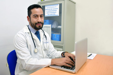 young doctor on a desk working on laptop