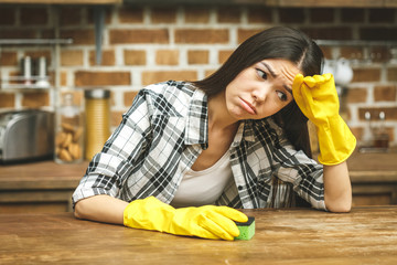 Woman in protective gloves with spray is relaxing after cleaning her house, close-up. Home interior