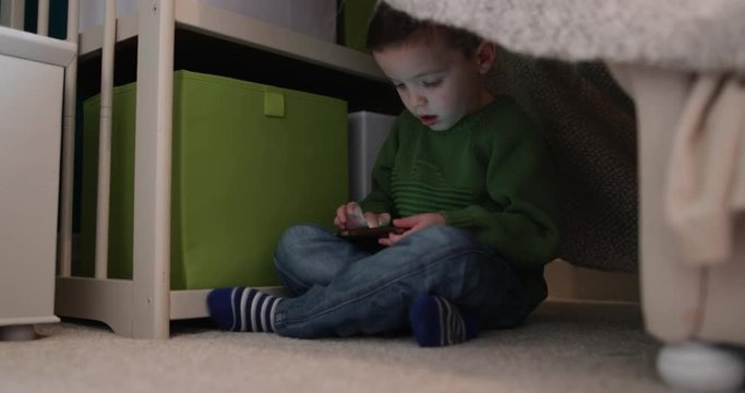 Preschool boy playing with smartphone in den