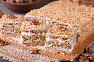 Homemade cake with honey, walnuts, cream on wooden desk background