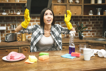 Young attractive angry and upset woman or housewife cleaning her kitchen room with cloth and spray bottle tired and frustrated in lazy homework and domestic stress concept