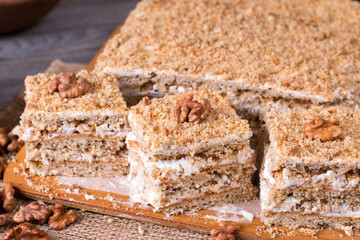 Homemade cake with honey, walnuts, cream on wooden desk background