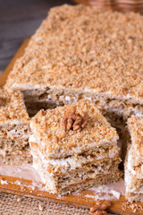 Homemade cake with honey, walnuts, cream on wooden desk background