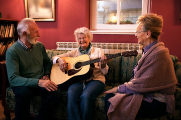 Group of senior friends playing guitar and having fun at nursing home