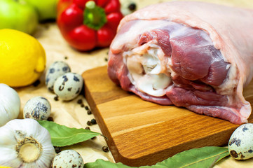 Raw turkey thigh garlic apples lemon quail eggs spices on a wooden board. Top view of a turkey, knife on a beige paper background. Culinary background, ingredients for cooking.