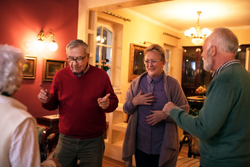 Funny senior people smiling and dancing at home party