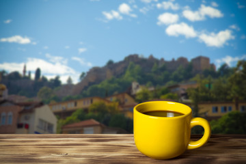 Yellow cup with tea on wooden table opposite a defocused  background. Collage. Selective focus. Toned