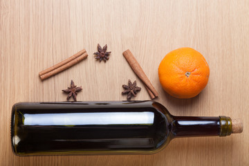 Fresh orange, bottle of vine and spices on a light wooden table
