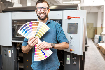 Funny portrait of typographer standing with color swatches at the printing manufacturing