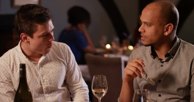 4K 2 Young men enjoying a meal out, man feeds his companion with a taster from his plate