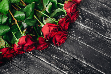 Fototapeta na wymiar beautiful scarlet roses on a black wooden background