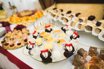 Delicious and tasty dessert table with cupcakes shots at reception closeup