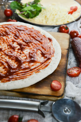 Ingredients for Pizza: basis dough, salami sausage, cherry tomatoes, grated cheese, tomato paste, herbs and arugula. Natural Wooden Background With Linen Napkin and Knife For Pizza