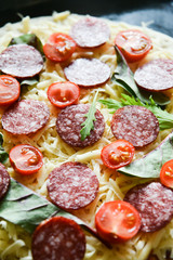 Ingredients for Pizza: basis dough, salami sausage, cherry tomatoes, grated cheese, tomato paste, herbs and arugula. Natural Wooden Background With Linen Napkin and Knife For Pizza