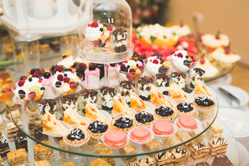 Delicious and tasty dessert table with cupcakes shots at reception closeup