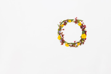 Meadow leaves and flowers in wreath on white background, flat lay