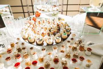 Delicious and tasty dessert table with cupcakes shots at reception closeup
