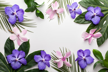 Green tropical leaves and exotic flowers on white background. Flat lay, top view.