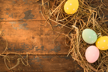 Easter eggs and hay on a wooden background with empty space