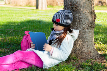 Child reading the book outdoors in the park