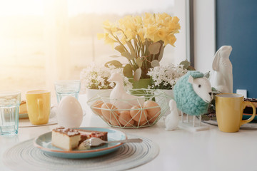 Pastel Easter table with eggs, flowers and cake, close up