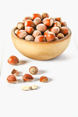 Hazelnut nuts in a wooden bowl on a white wooden table. Superfood.