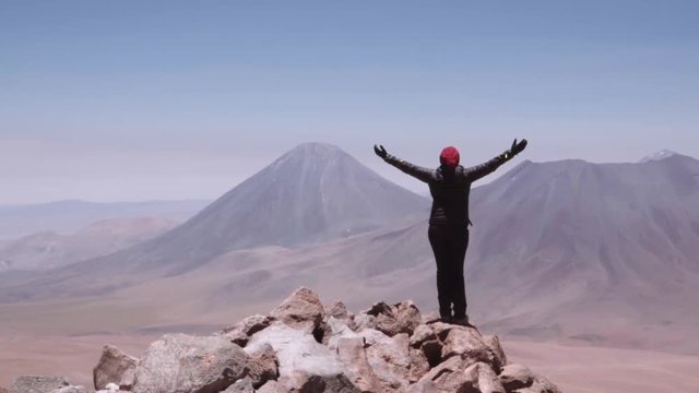 Female hiker on the peak of volcano contemplating the incredible horizon, Andean mountain range.