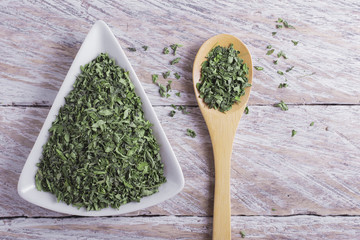 powder and moringa leaves in bowl on rustic wooden background