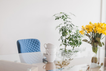 Glass table top with cups and spring bouquet with daffodils and eucalyptus