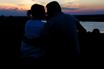 Young couple silhouette against sunset sky. Romantic evening.